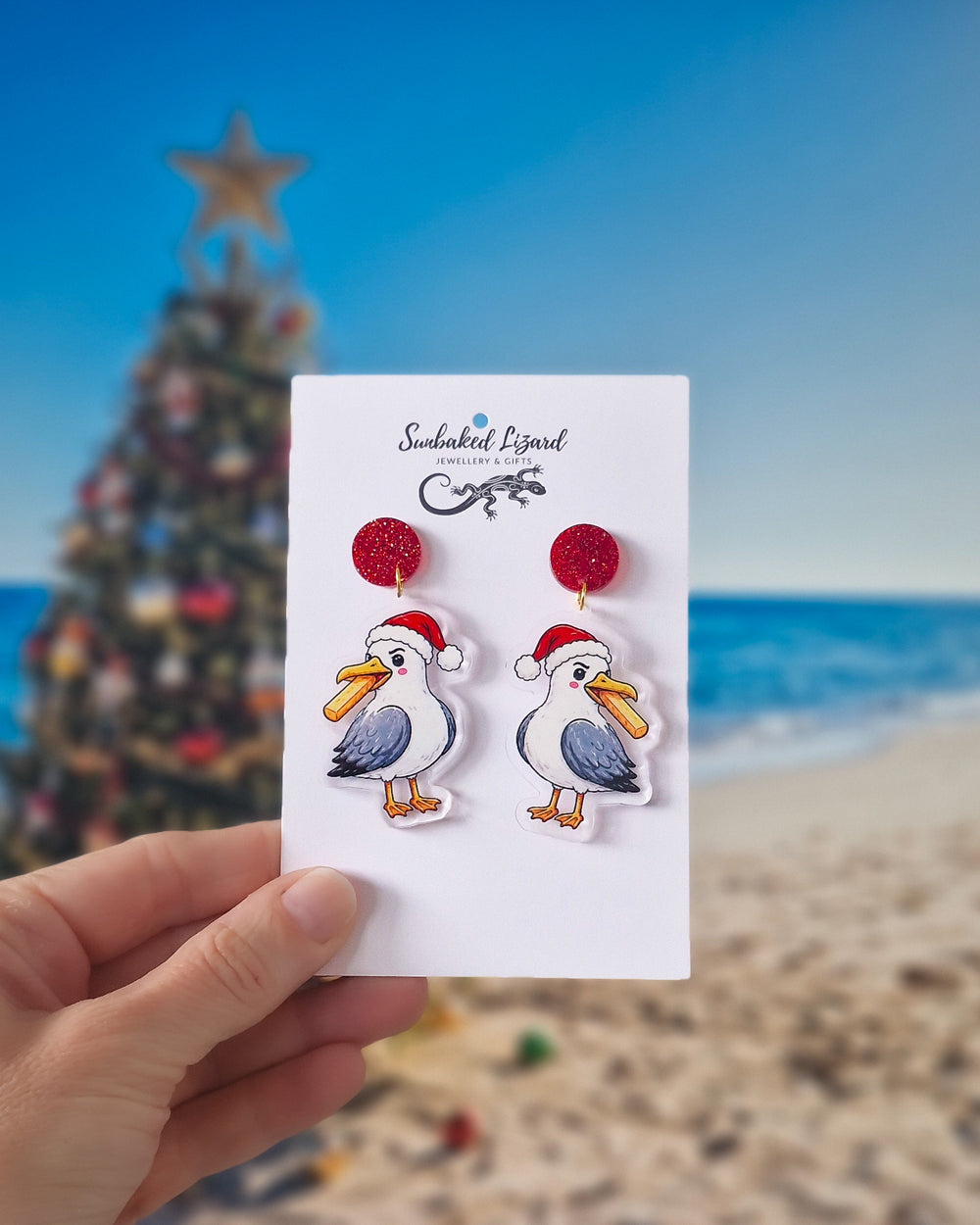 Christmas seagull earrings with red glitter tops, Santa hats and hot chips on a beach Christmas background.