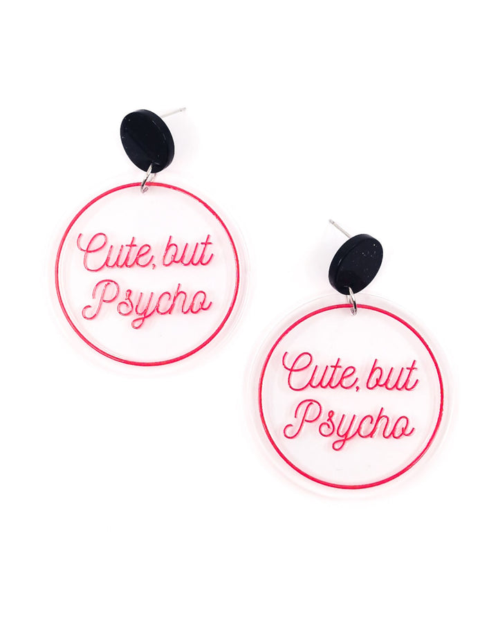 Cute But Psycho acrylic statement earrings with pink lettering on clear round drops and black glitter studs.