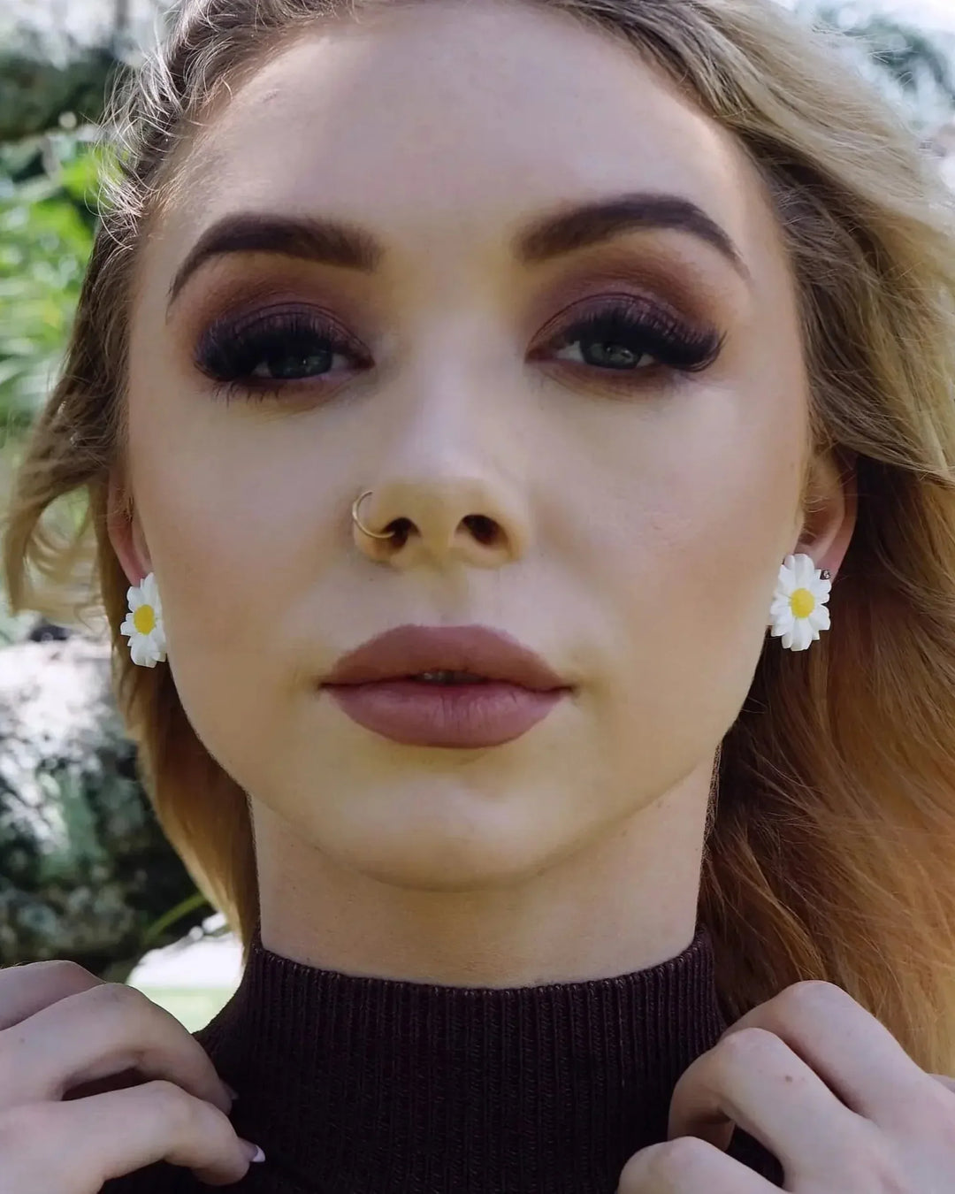 Model wearing white daisy stud earrings with yellow centre outdoors in natural light