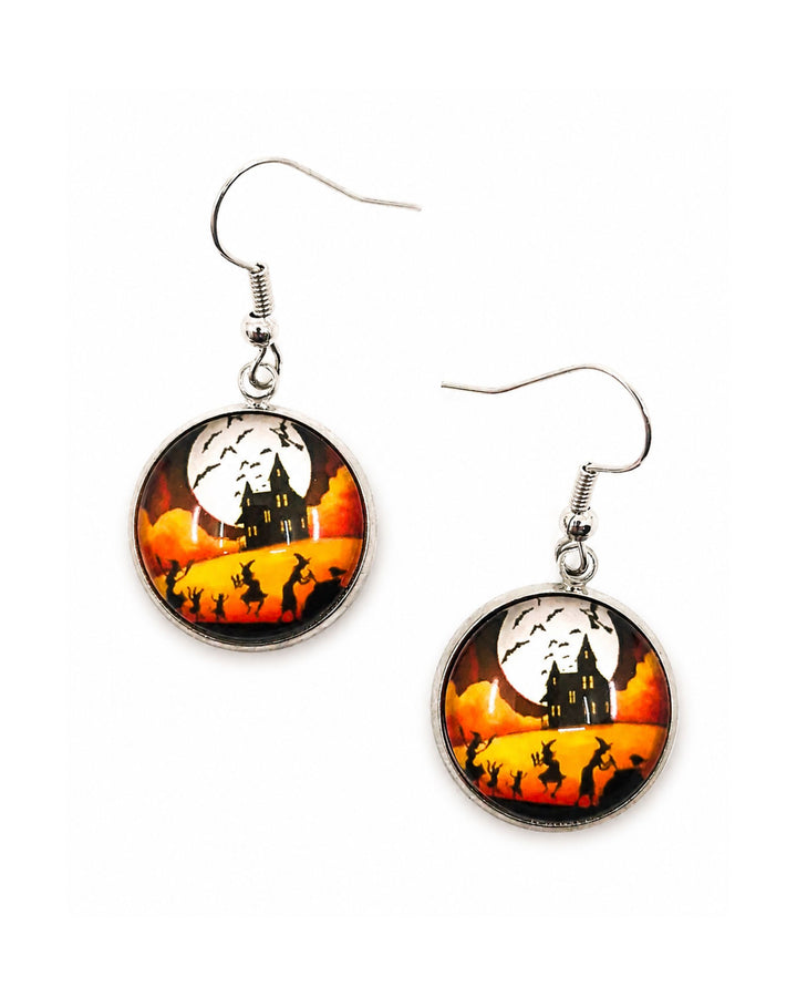 Round glass Halloween earrings showing witches dancing before a haunted house under a full moon, silver hooks