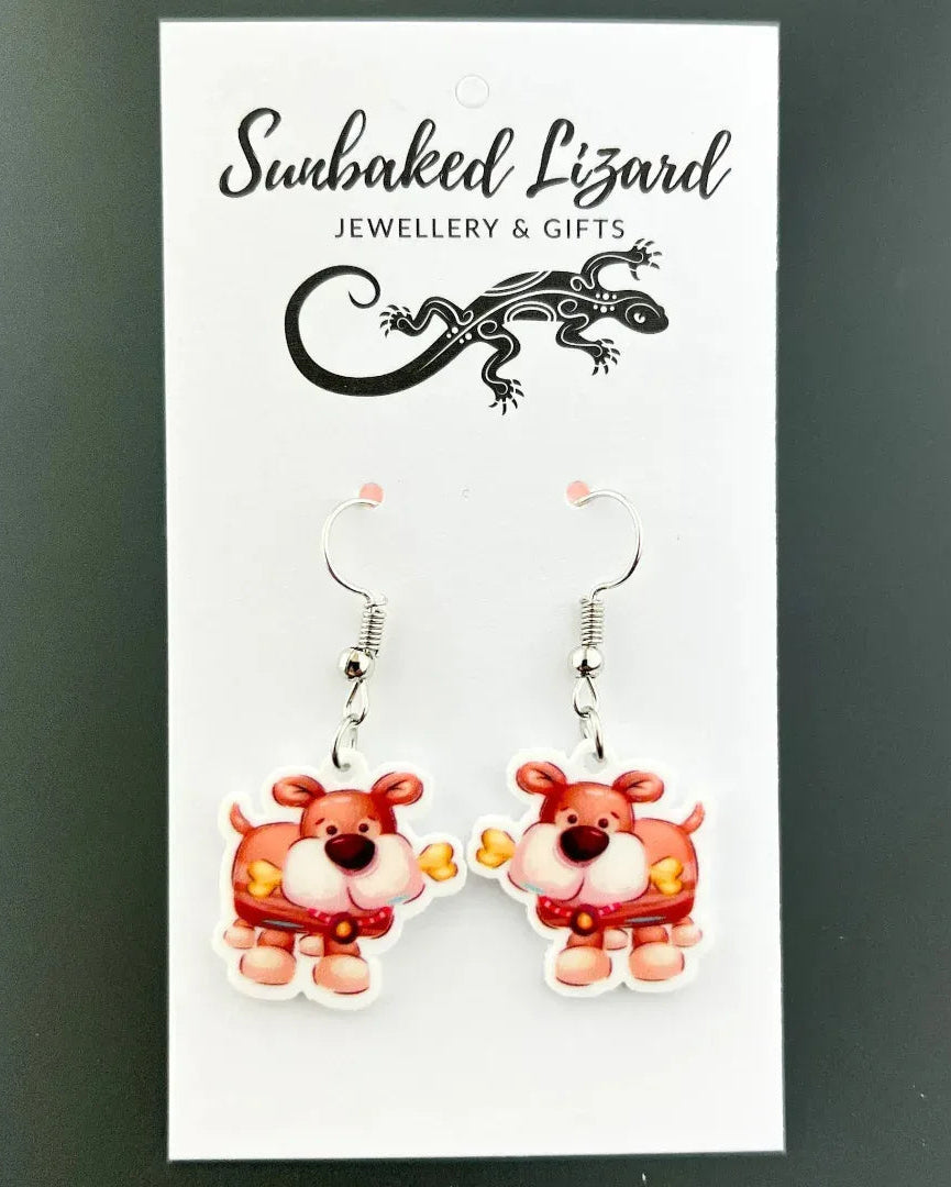 Doggy Got a Bone drop earrings, rose-pink puppy charm with dog bones on silver hooks on a Sunbaked Lizard backing card