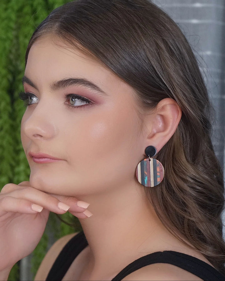 Earthy resin drop earrings worn on ear showing round shape, timber-style pattern, and black stud