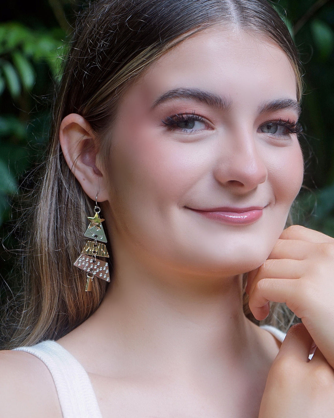Model wearing Elegant Christmas Tree Earrings with layered silver and gold Christmas tree charms, perfect for festive outfits.