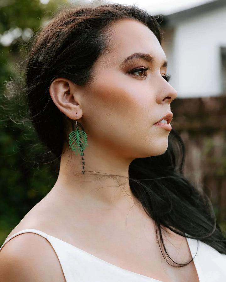 Model wearing black filigree leaf drop earrings showing size and open leaf detail