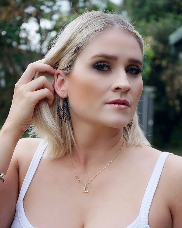 Model wearing black filigree leaf drop earrings showing size and lightweight leaf shape