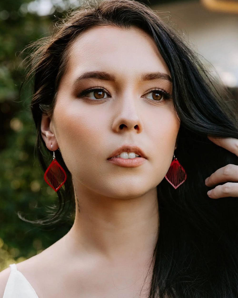 Model wearing red filigree teardrop drop earrings with fine lined cut-out detail