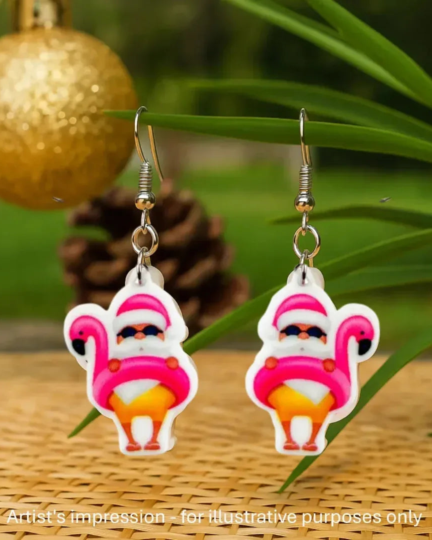 Flamingo floaty Santa Christmas earrings hanging beside a gold bauble and palm leaves