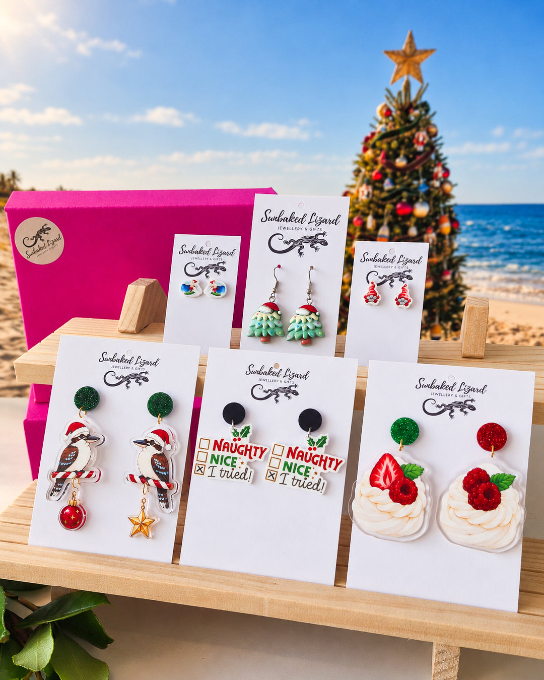 Fun Xmas Earrings Gift Box, six pairs of Christmas earrings on Sunbaked Lizard cards, including a kookaburra and a pavlova, with a Christmas tree on the beach behind