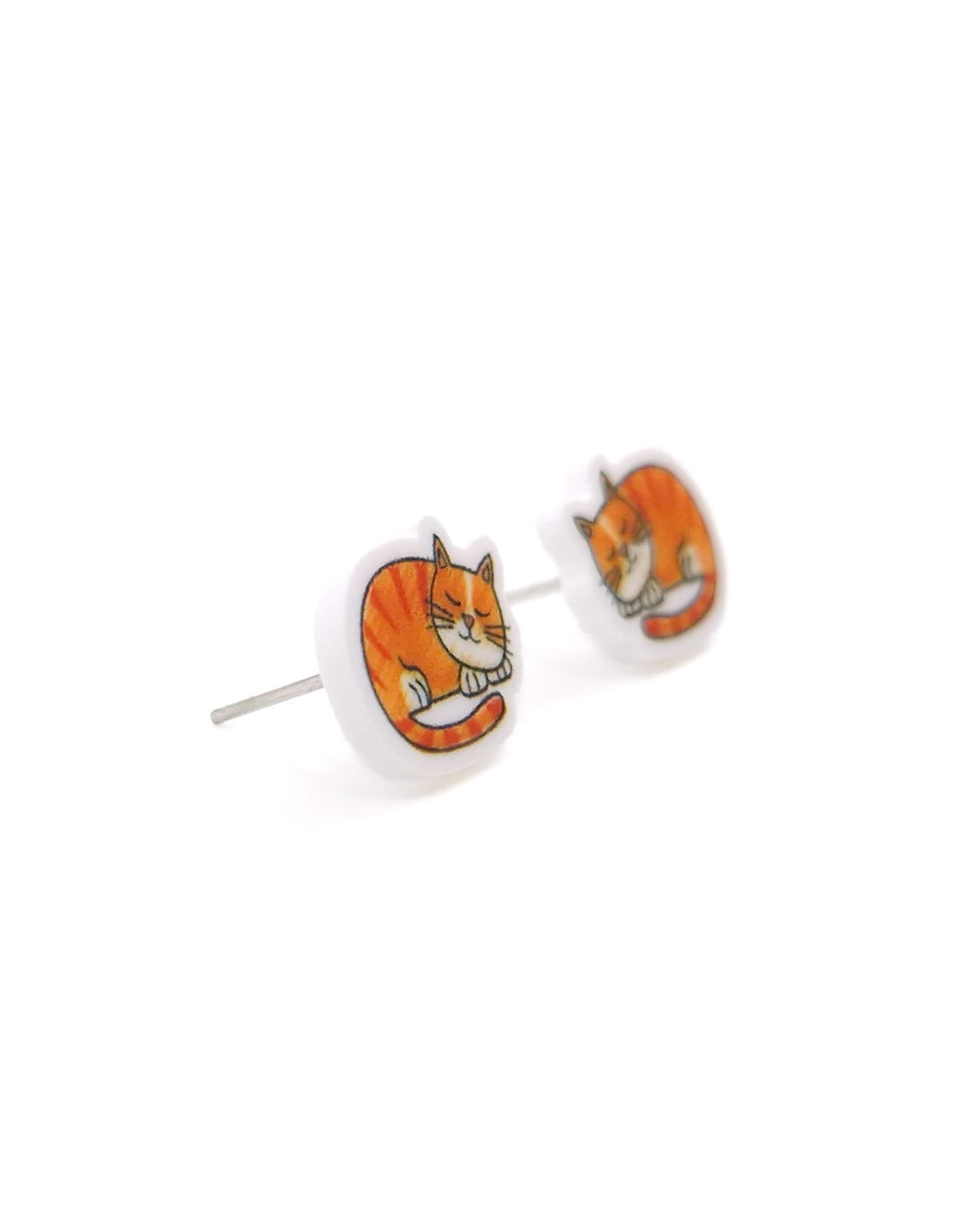Close-up angled view of ginger cat stud earrings with sleeping orange tabby acrylic charms and silver posts.