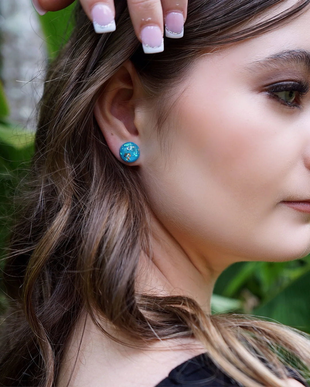 Blue gold and opal fleck stud earrings worn on ear with glossy dome finish