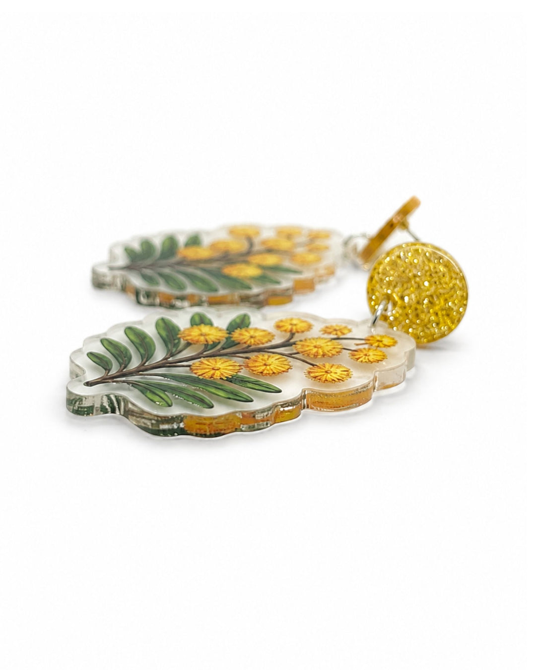 Side view of golden wattle earrings showing the flat clear acrylic charm and the gold glitter stud