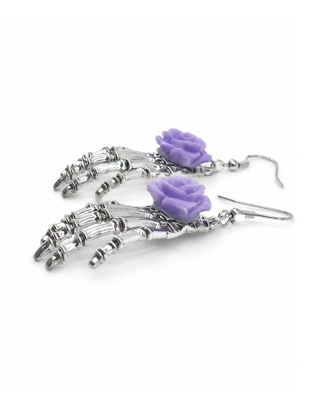 Halloween skeleton hand earrings with silver bone hands and purple rose charms, laid flat on a white background