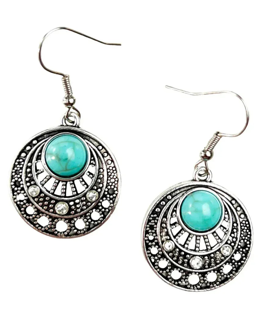 A pair of Gypsy Turquoise Earrings showing the intricate antiqued silver metalwork and round turquoise stone.