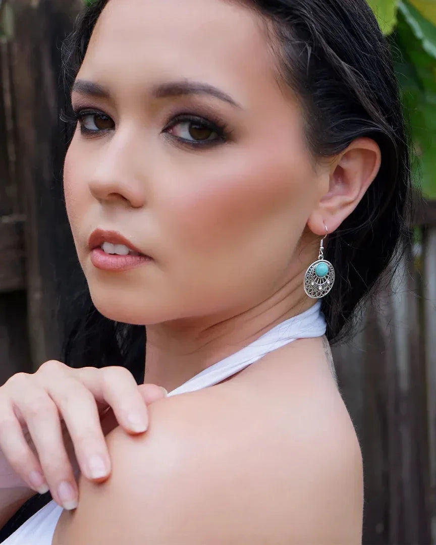 Model wearing Gypsy Turquoise Earrings featuring a round silver sunburst design and a turquoise stone in the centre.