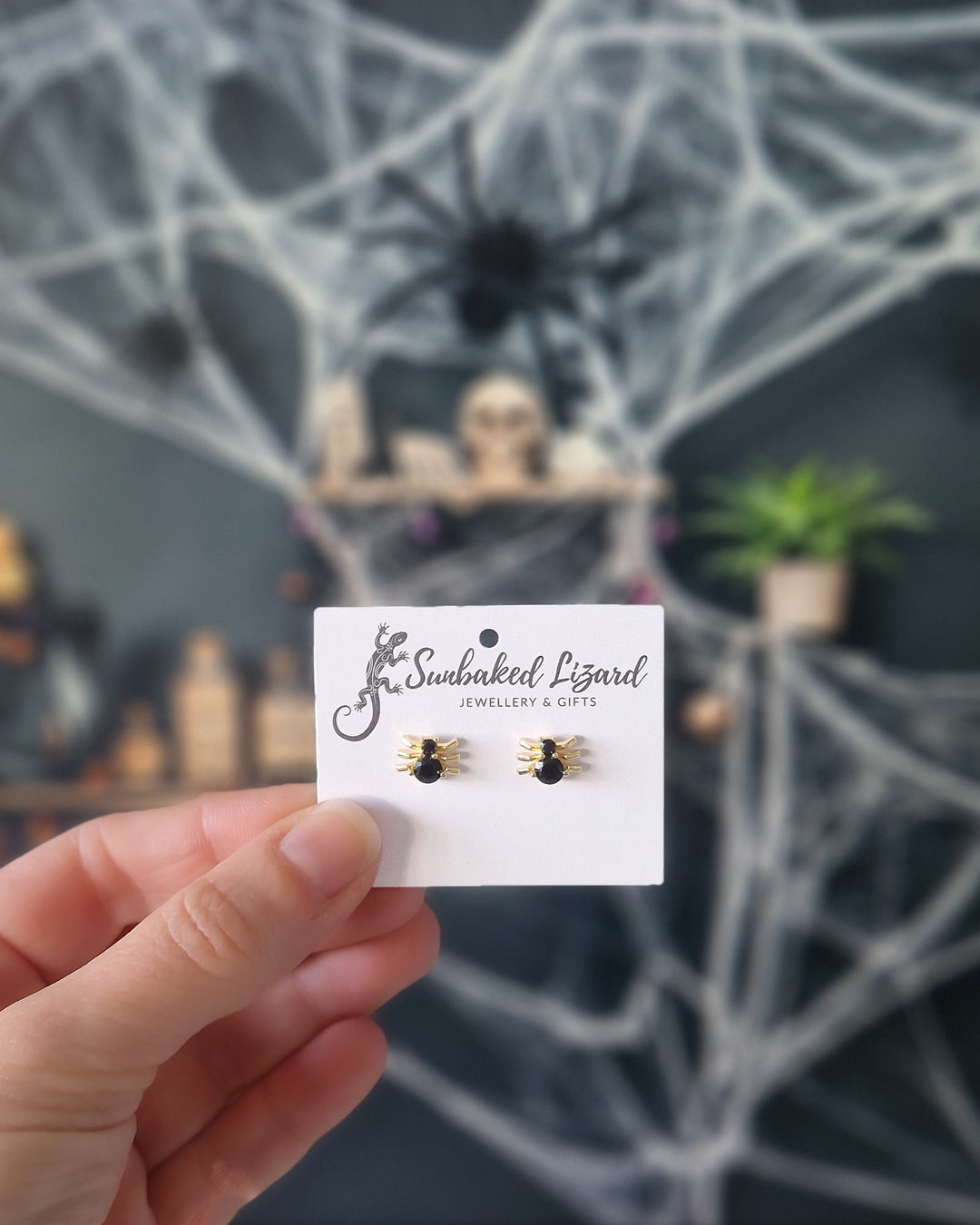 Small Halloween spider earrings on Sunbaked Lizard card in front of a spiderweb display