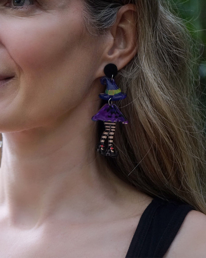 Detailed view of Witch Stud Drop Earrings featuring purple witch outfits, striped legs and black shoes for Halloween.