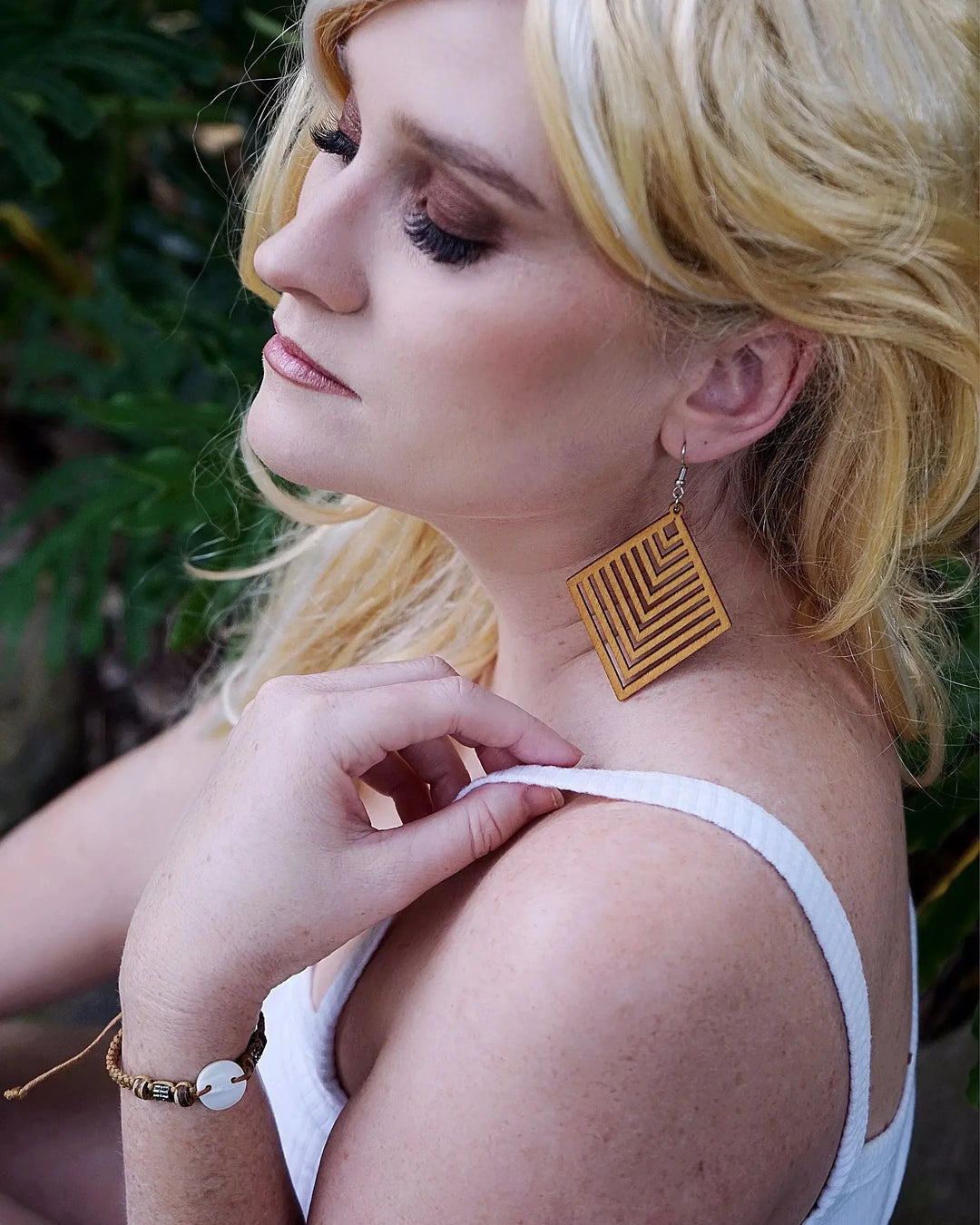 Close-up of model wearing Izzy geometric diamond timber drop earrings with chevron cut-out