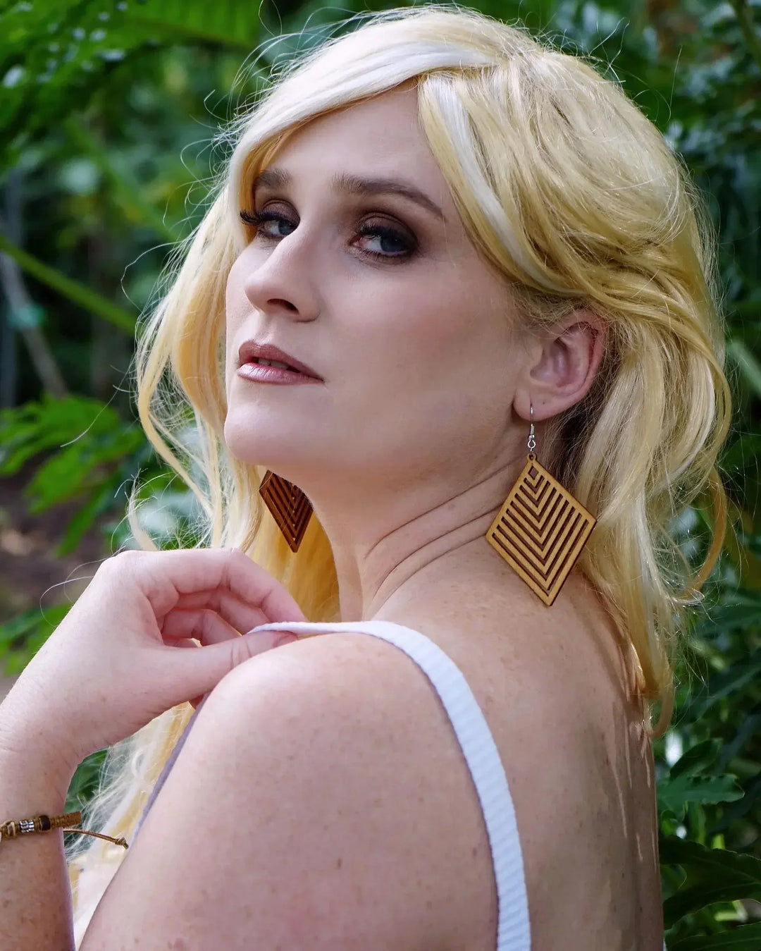 Side view of model wearing large diamond shaped timber earrings with chevron pattern