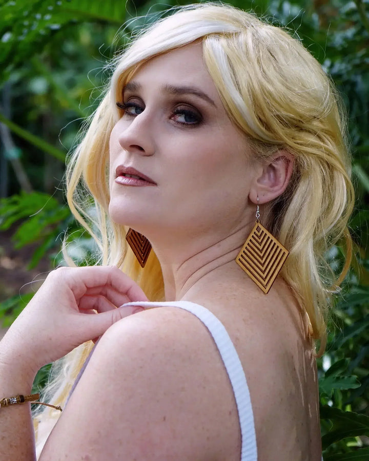 Side view of model wearing large diamond shaped timber earrings with chevron pattern