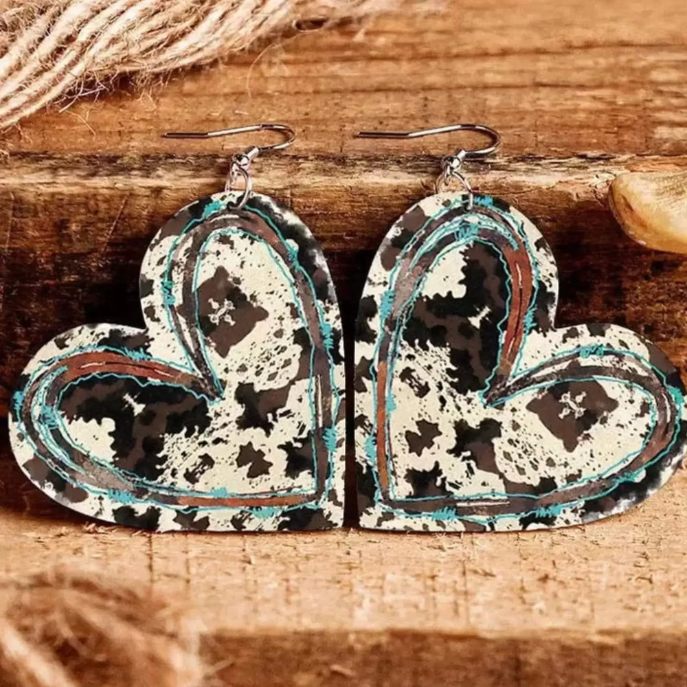 Close up of cow print leather heart drop earrings, lightweight statement jewellery