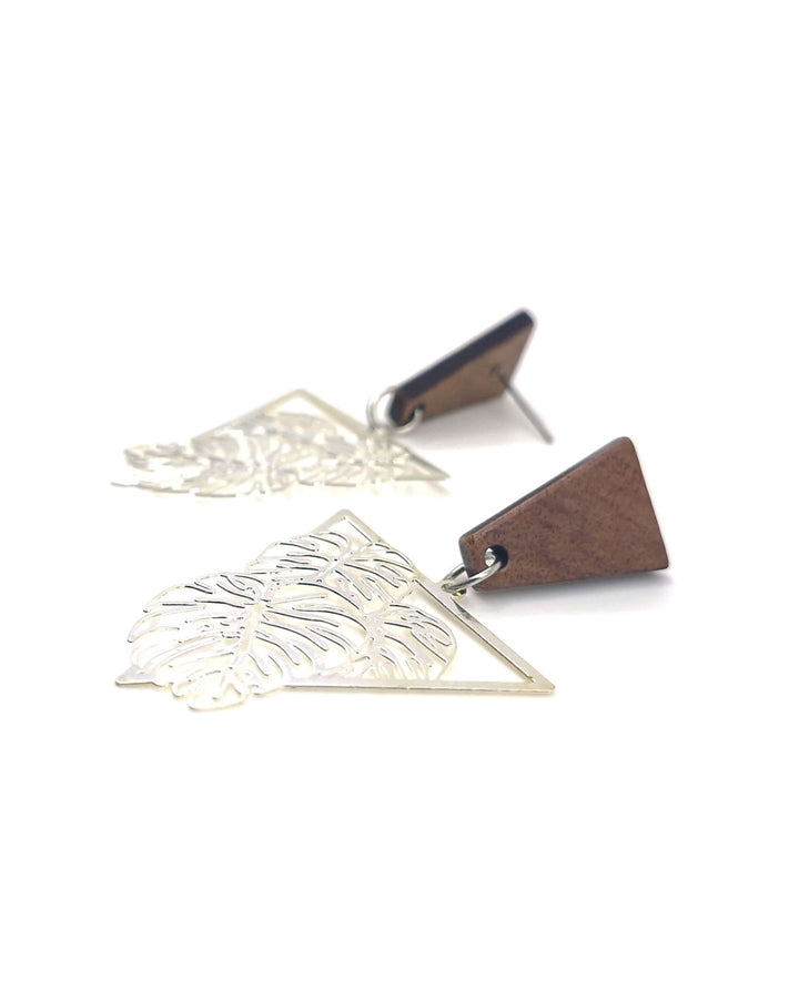 Detail photo of timber and metal monstera leaf statement earrings on a white background