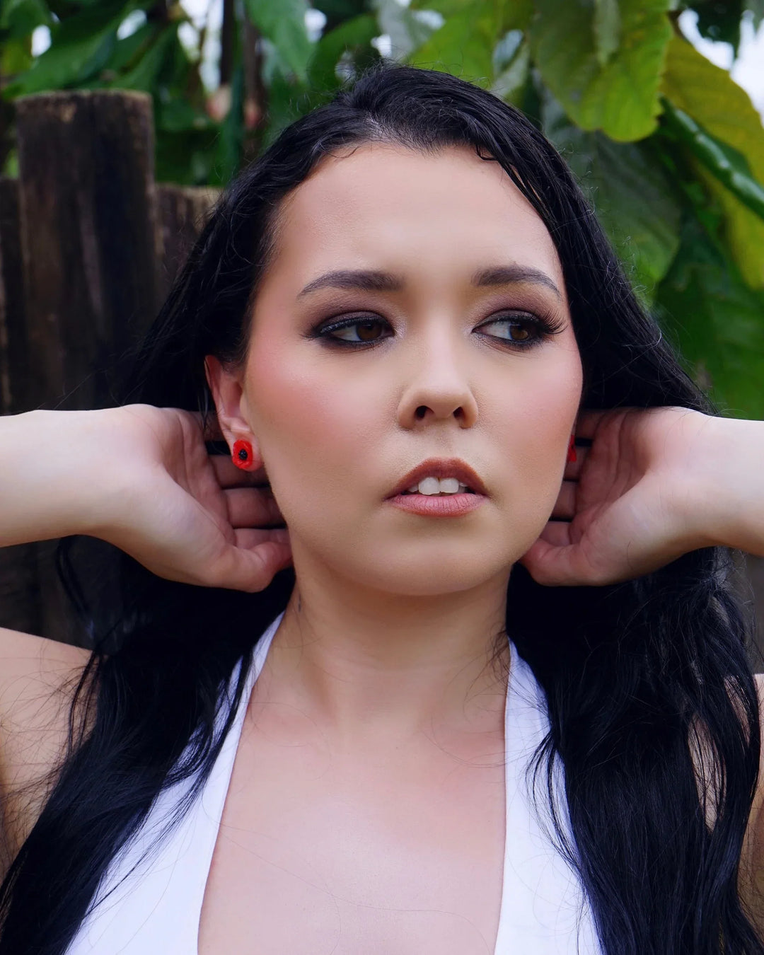 Woman wearing petite red poppy stud earrings with black centre
