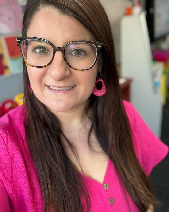 Pink Acrylic Woven Earrings with black tops worn with a bright pink outfit.