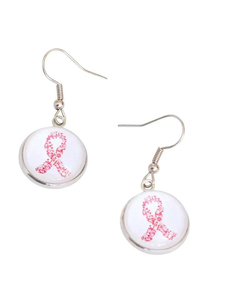 Close-up of pink ribbon drop earrings, a glass cabochon in a silver-tone setting on stainless steel hooks