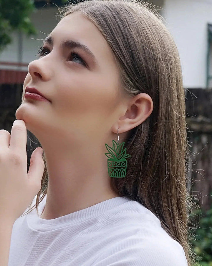 Model wearing green potted plant statement earrings, showing the 60mm size against the jaw