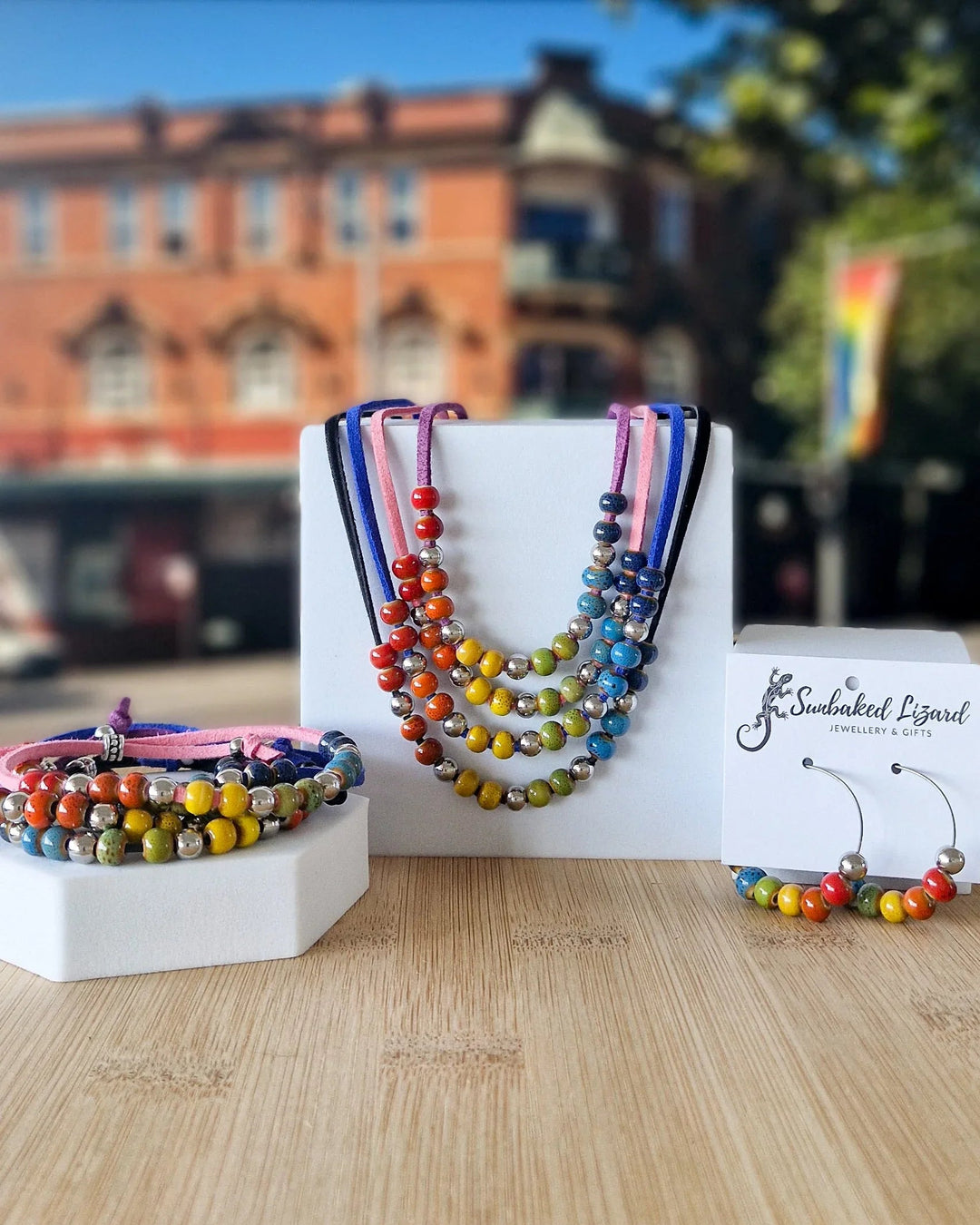Rainbow Pride jewellery set with matching necklace, bracelet and hoop earrings displayed with colourful beads