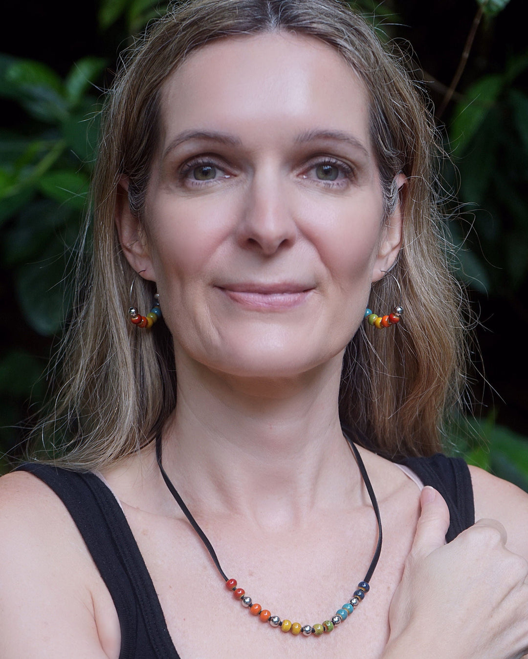 Model wearing Rainbow Pride hoop earrings and matching necklace with rainbow ceramic beads for Pride and Mardi Gras