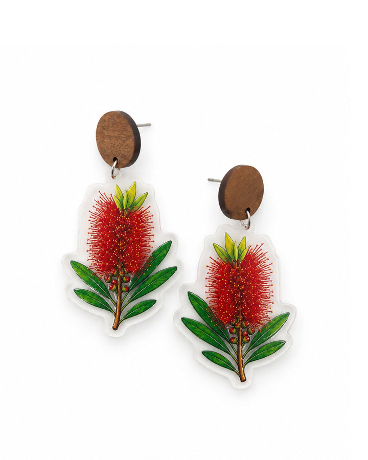 Red bottlebrush earrings with green leaves printed on clear acrylic, hanging from wooden stud tops