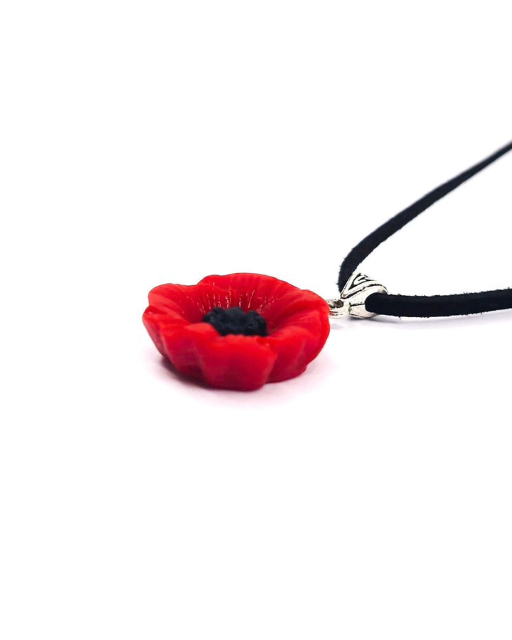 Close-up of red poppy necklace pendant showing raised petals, black centre and black cord