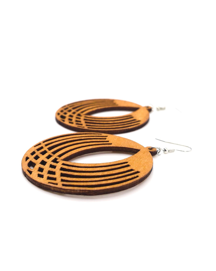 Large round geometrical timber drop earrings with cut-out pattern on a white background