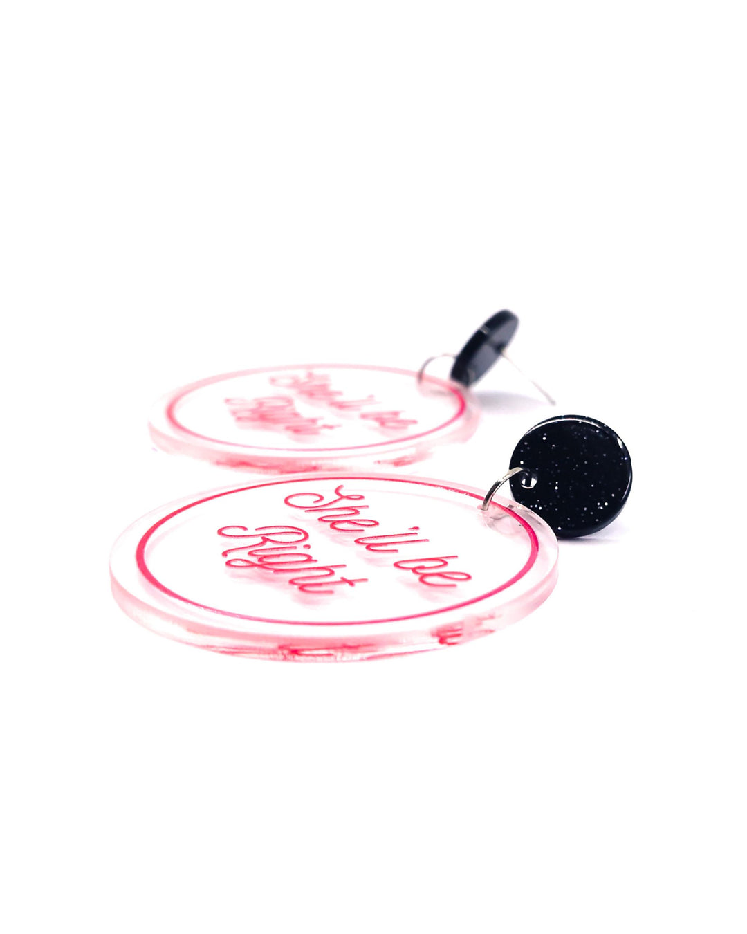 Close-up of She’ll Be Right acrylic statement earrings with pink script, clear round charms and glitter black studs