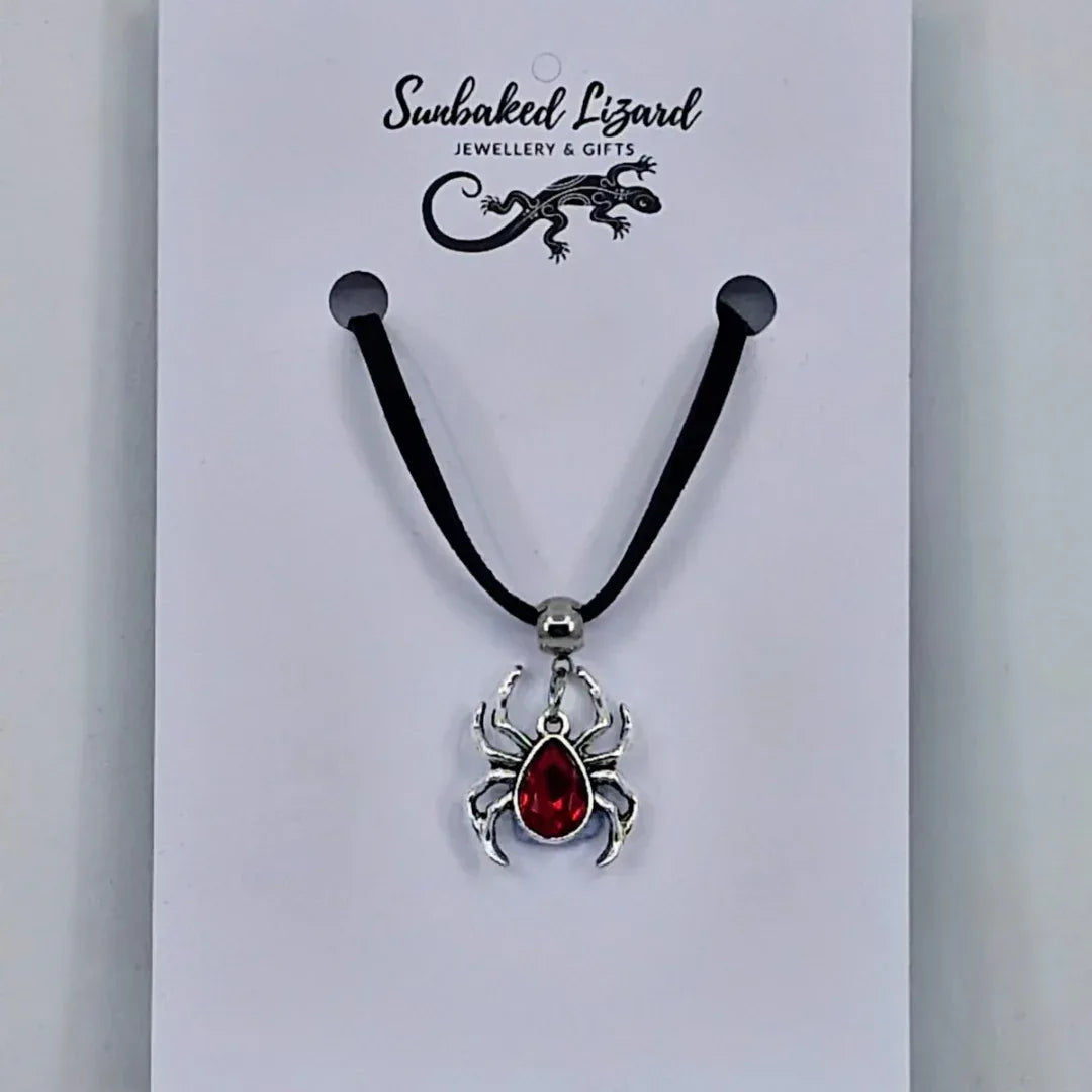 Silver spider pendant necklace with ruby-red gem-style body on black cord – creepy-cute Halloween jewellery