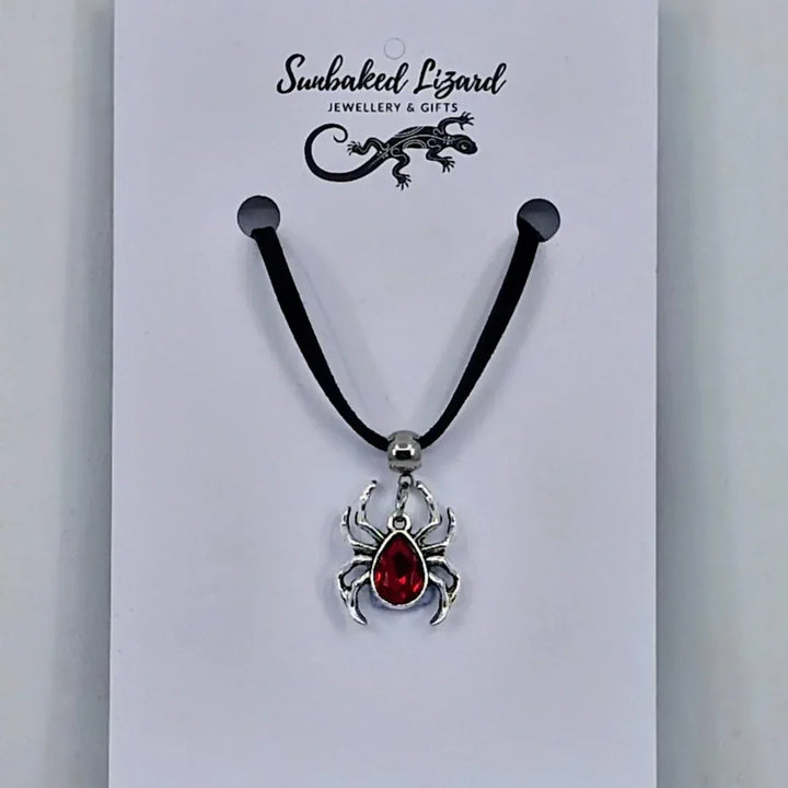 Silver spider pendant necklace with ruby-red gem-style body on black cord – creepy-cute Halloween jewellery