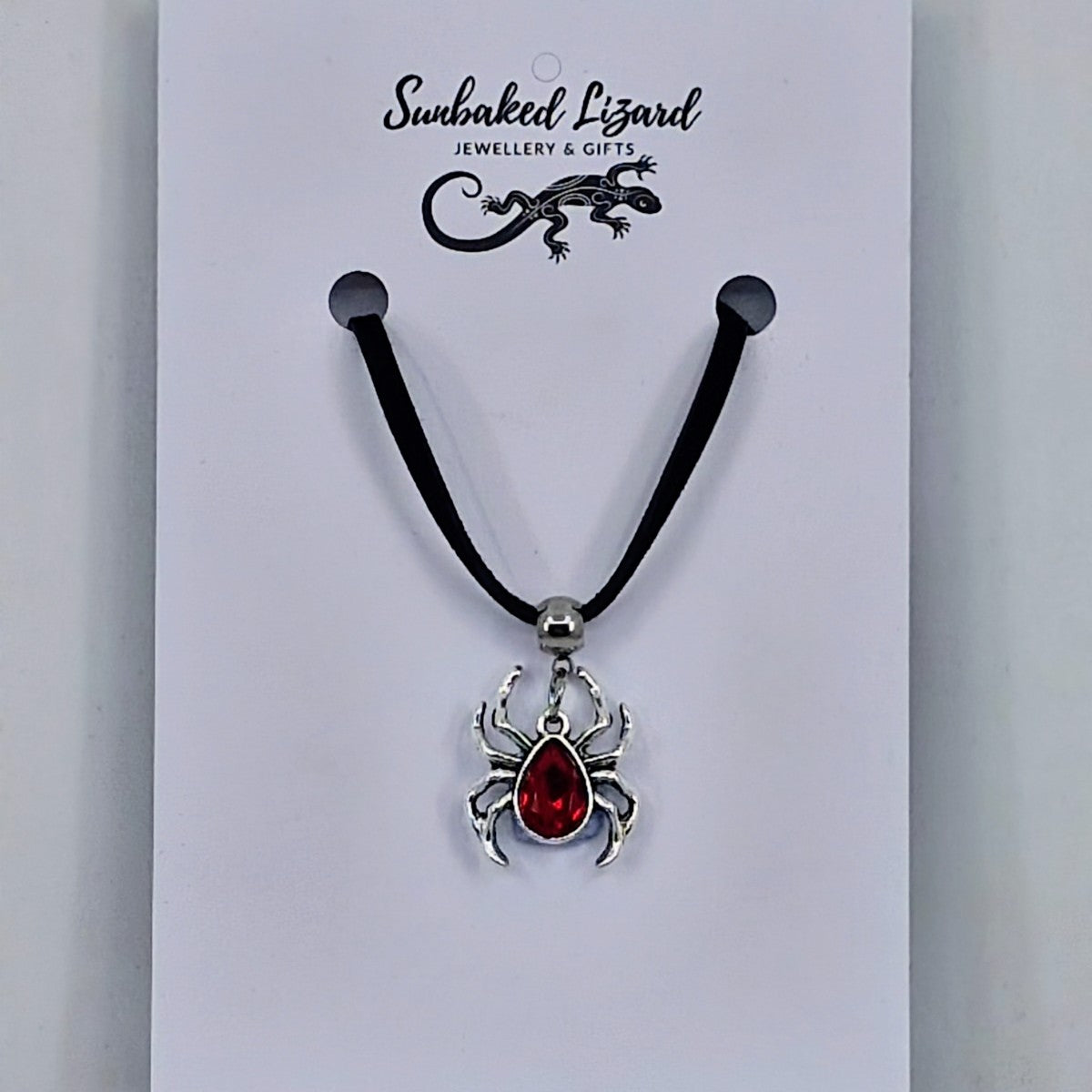 Silver spider pendant necklace with ruby-red gem-style body on black cord – creepy-cute Halloween jewellery