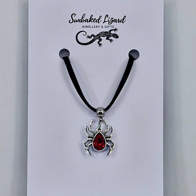 Silver spider pendant necklace with ruby-red gem-style body on black cord – creepy-cute Halloween jewellery