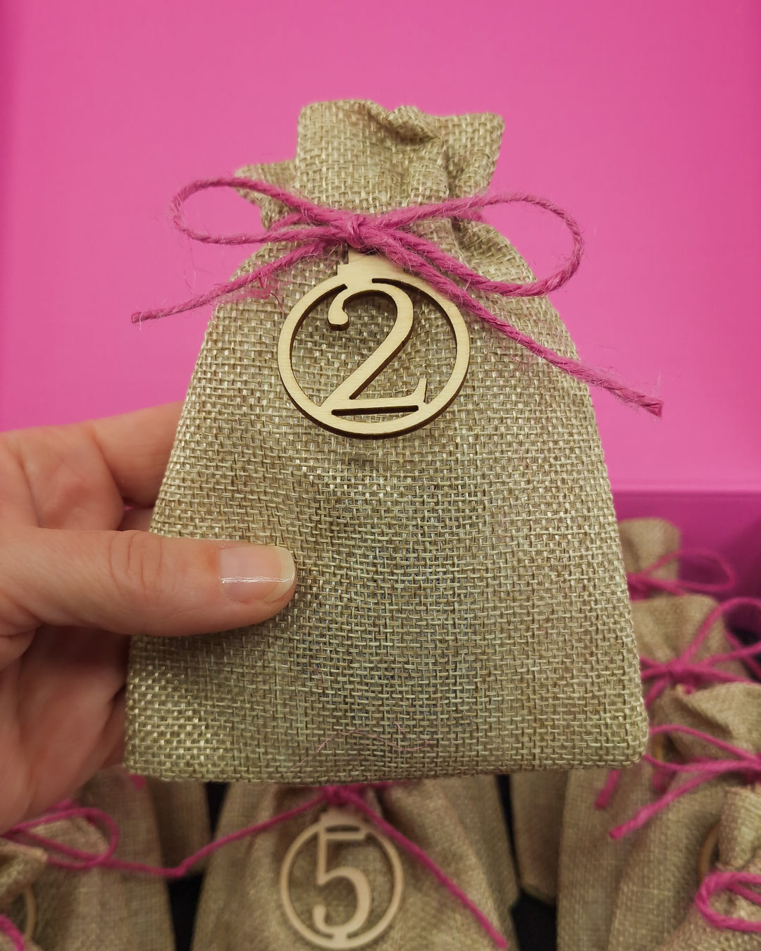 Open Sunbaked Lizard 12 Day Jewellery Advent Calendar with a hand holding one of the numbered burlap gift bags showing scale.