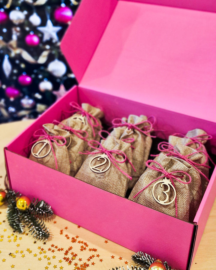 Open Sunbaked Lizard 12 Day Jewellery Advent Calendar showing numbered burlap gift bags inside a pink gift box for Christmas 2026.