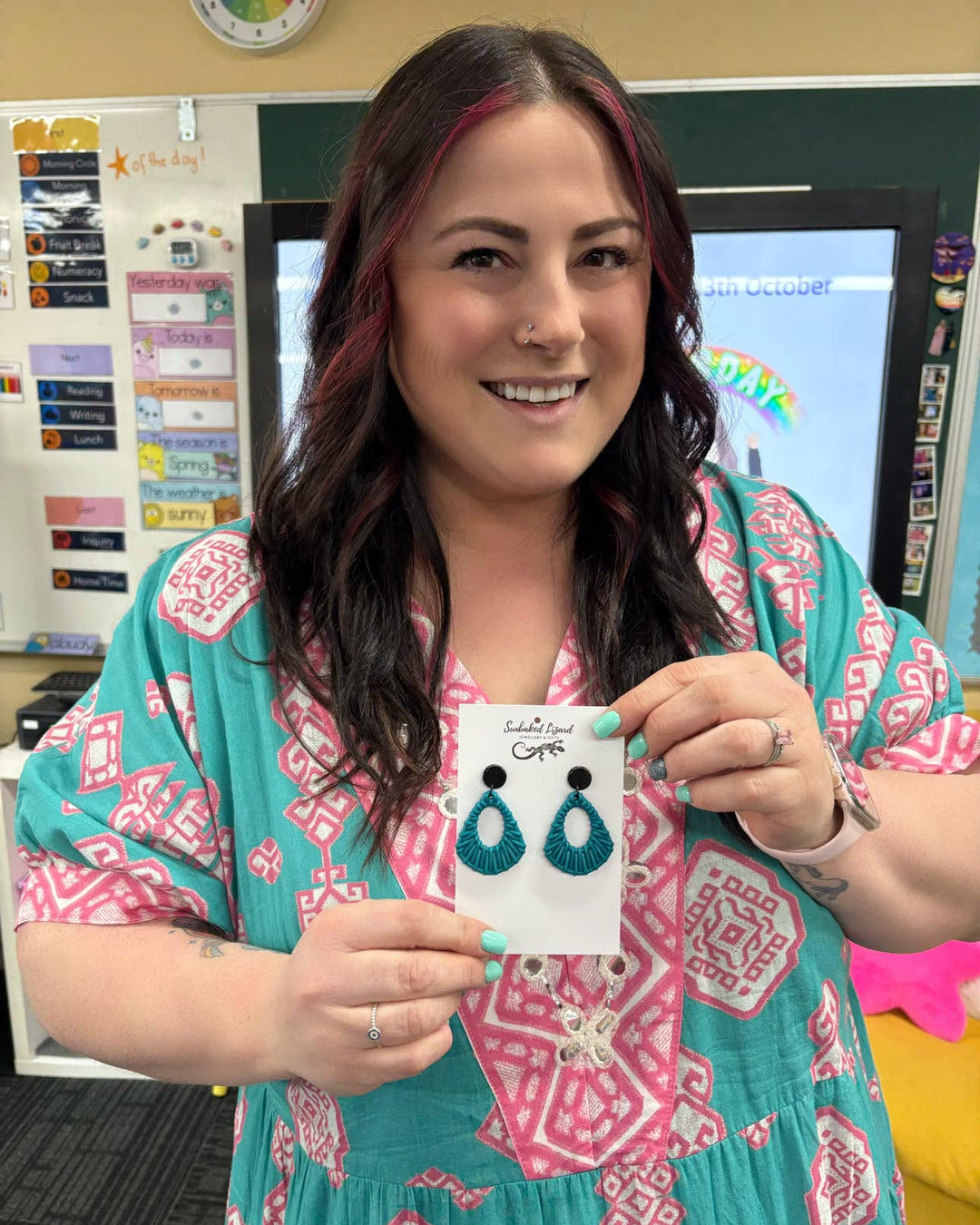 Teal Acrylic Woven Earrings with black tops displayed on a Sunbaked Lizard product card in a classroom.