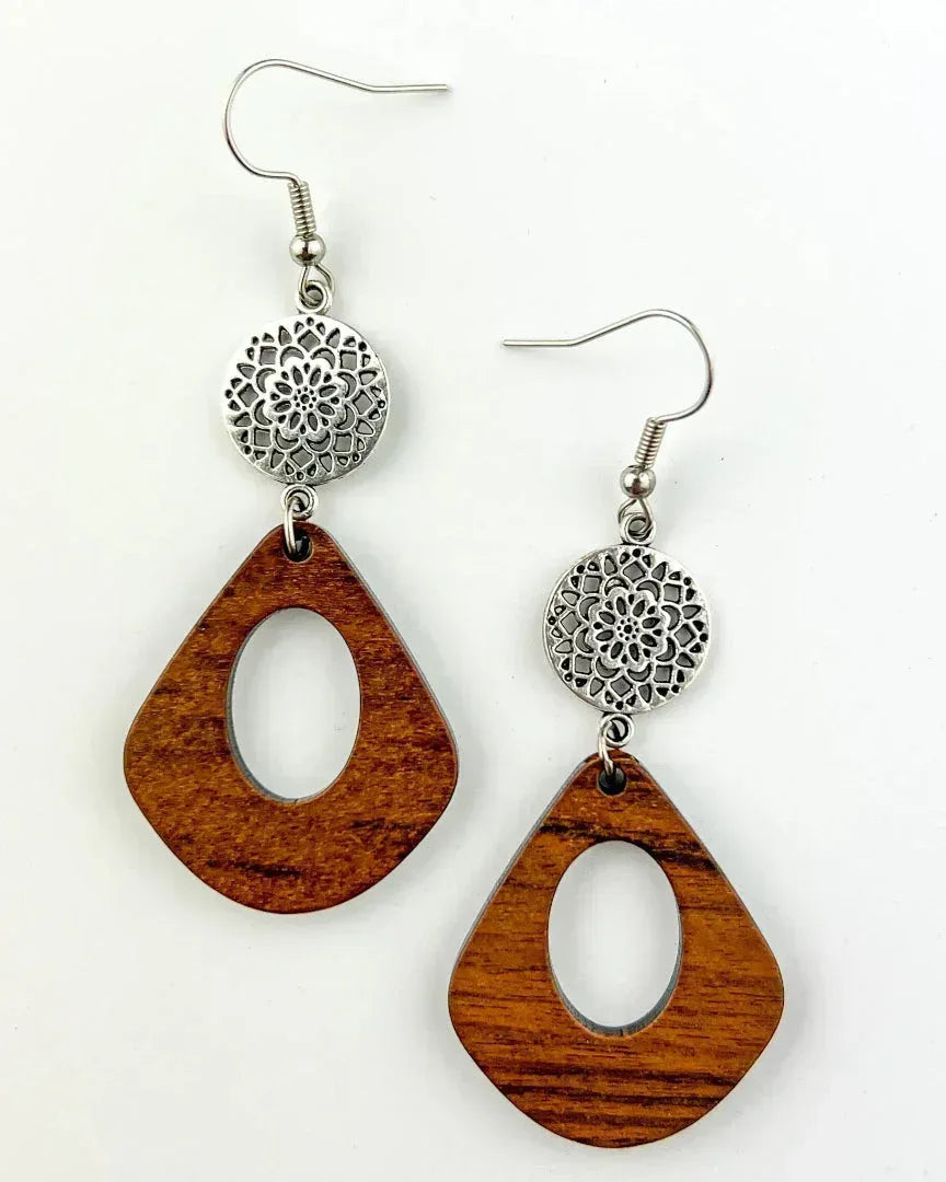 Close up of timber drop earrings with oval cut-out and silver mandala disc