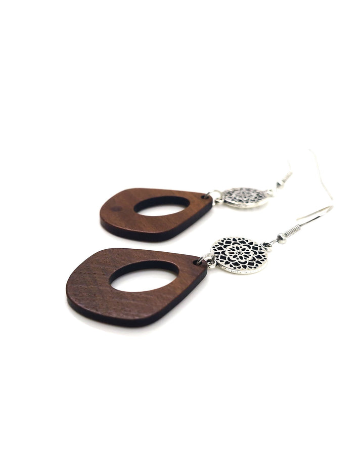 Detail view of timber drop earrings with oval cut-out and silver mandala disc