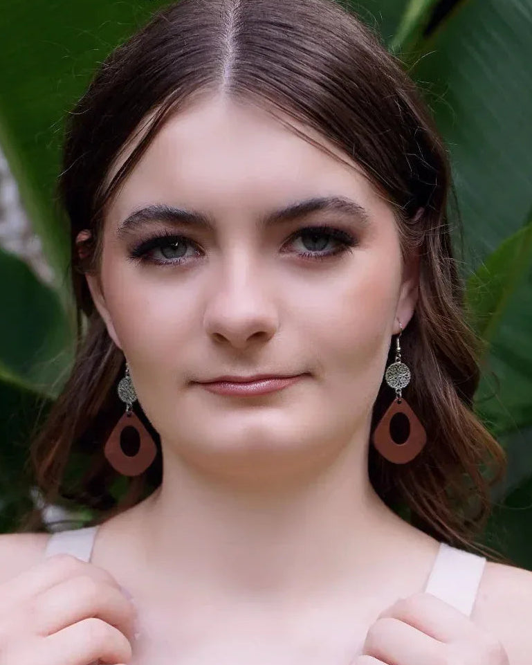 Front view of model wearing wooden drop earrings with silver filigree accent