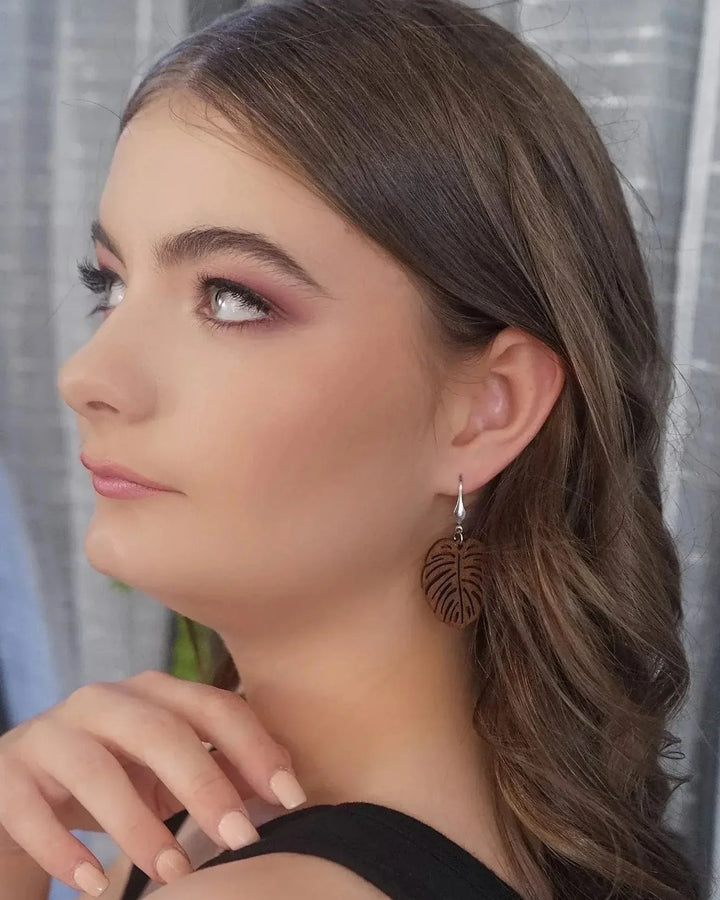 Brunette model wearing timber monstera leaf drop earrings with silver hooks