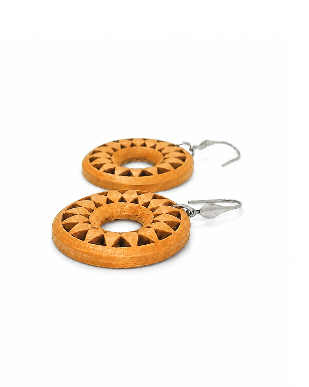 A pair of wooden dangle earrings with a carved geometric sunburst pattern, attached to silver fishhook wires, shown on a plain white background.