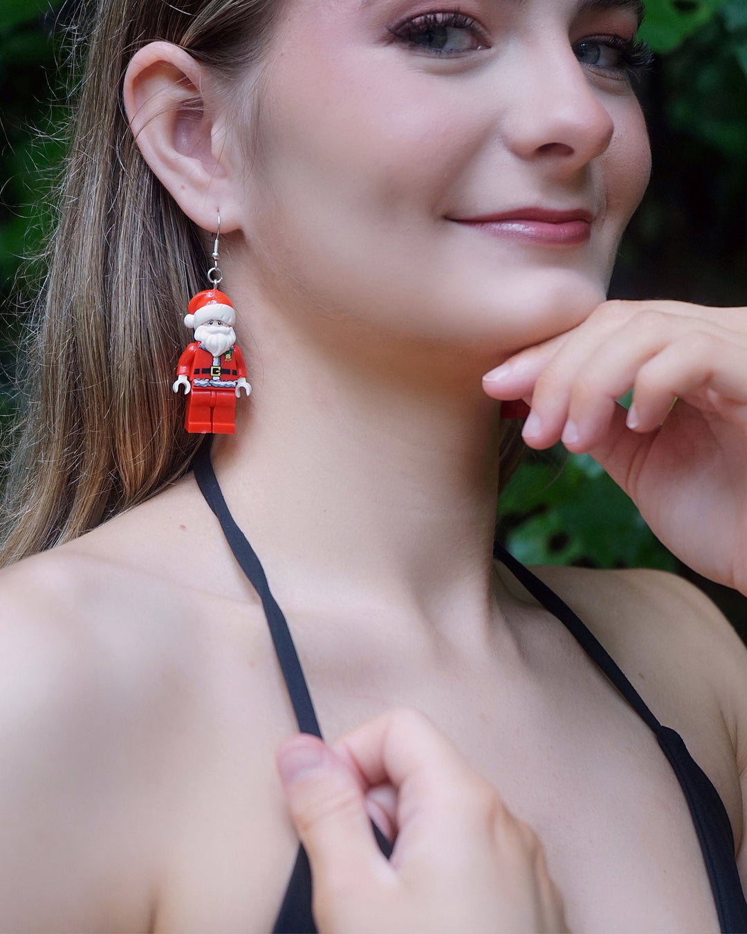 Close-up of a model wearing Fun Toy Santa Christmas Earrings featuring bright red Santa charms with nostalgic toy-style detail.