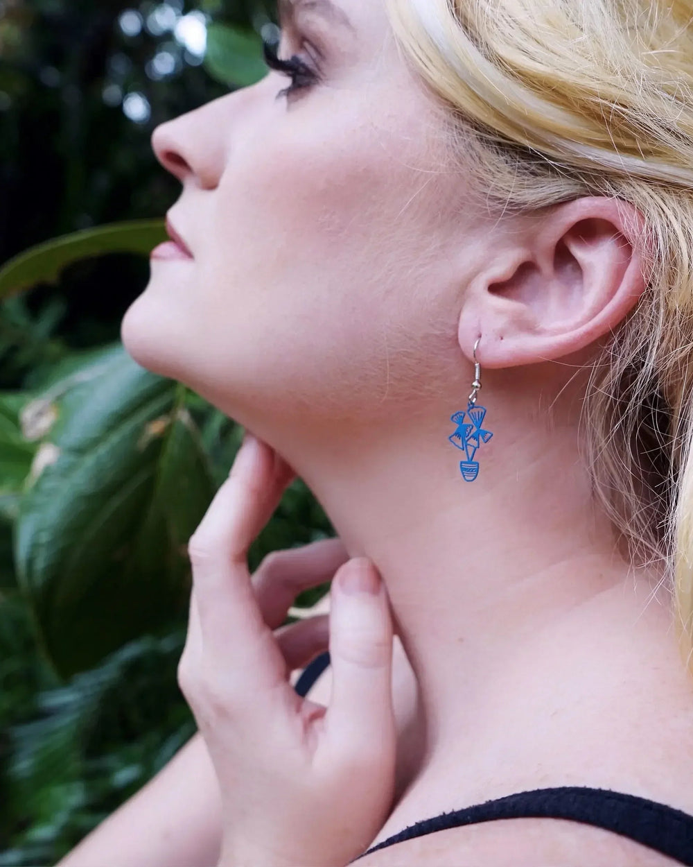 Model wearing blue tropical potted plant earrings, showing the small size against the ear