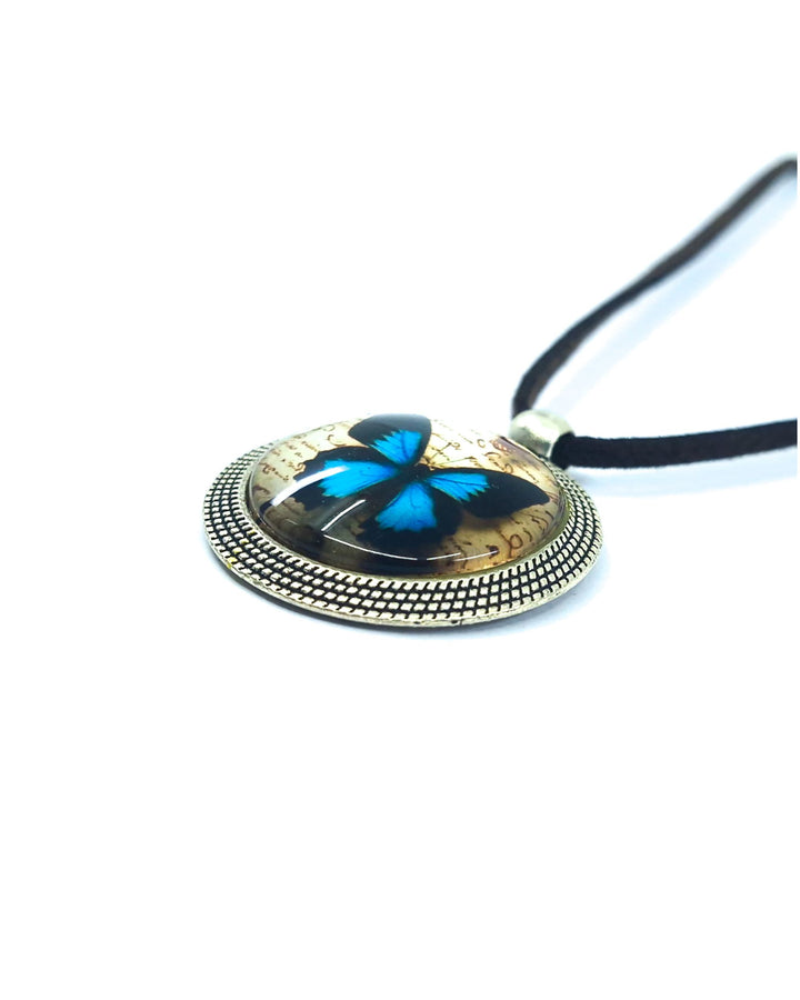Close-up of Ulysses butterfly necklace pendant with blue butterfly design, silver frame and black cord